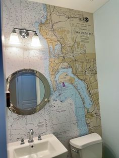 a bathroom with a map on the wall next to a white toilet and sink in it