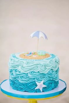 a cake with blue frosting and an umbrella on top