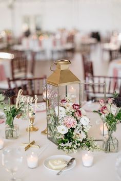 the centerpieces on this table are filled with flowers and greenery, along with candles