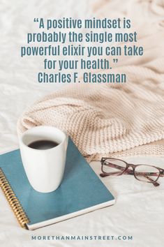 a cup of coffee on top of a book next to a pair of eyeglasses