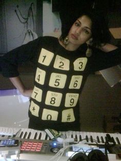 a woman standing in front of a keyboard wearing a t - shirt with numbers on it