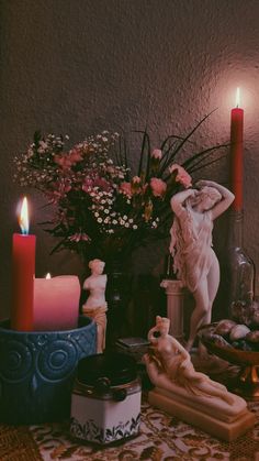 a table topped with candles and figurines next to a vase filled with flowers