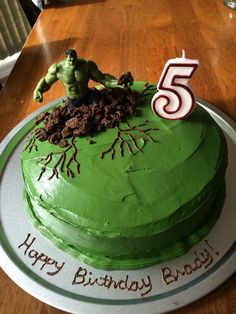 a green birthday cake with the number five on it's top and an incredible hulk figure