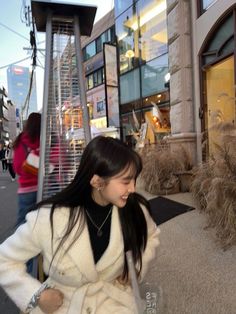 a woman is walking down the sidewalk in front of a store