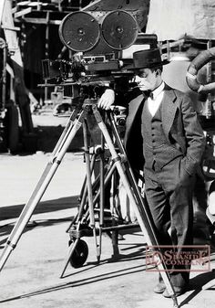 a man standing next to a camera on top of a tripod