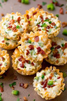 several mini pizzas with cheese and bacon in them sitting on a table next to green peppers