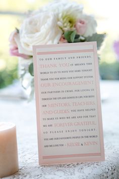 a pink and white wedding thank you card next to a candle on a lace tablecloth