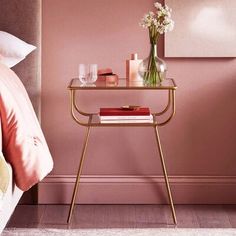 a bedroom with pink walls and a gold side table