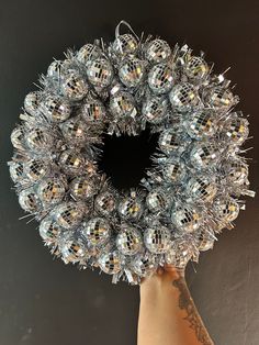 a hand holding up a wreath made out of tinsel