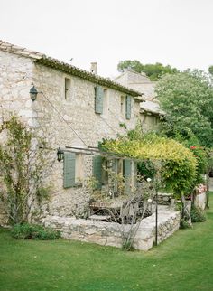 an old stone house with green shutters