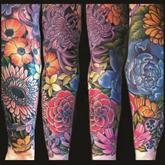 colorful tattoos on both legs and arms with flowers in the middle, all painted by an artist