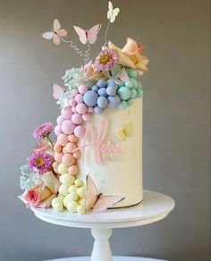 a white cake topped with lots of colorful candies and butterflies on top of it