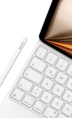 an open laptop computer sitting on top of a white table next to a pen and pencil