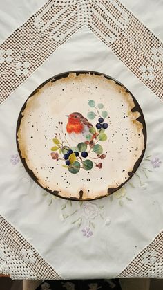 a plate with a bird painted on it is sitting on a tablecloth covered table