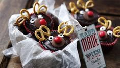 chocolate cupcakes decorated with reindeer noses and pretzels in wrappers on a wooden table