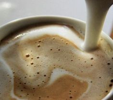 someone is pouring milk into a cup of coffee