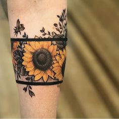 a sunflower tattoo on the leg with black and yellow flowers around it's center