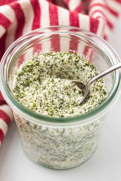 a jar filled with pesto sauce on top of a red and white striped towel