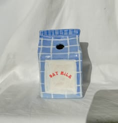 a blue and white ceramic container with a red cat in it's pocket on a white background