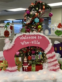 an office decorated for christmas with presents under the tree and welcome to who - vile sign