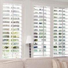 a living room filled with furniture and windows covered in white shuttered glass coverings