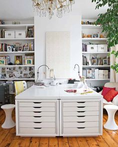 a white kitchen island with lots of drawers in the center and shelves full of books