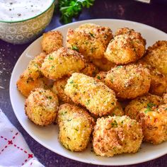 a white plate topped with fried food next to a bowl of dip