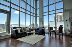 a living room filled with furniture and large windows overlooking the cityscape in the distance