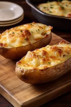 two baked potatoes sitting on top of a wooden cutting board