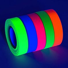 a roll of neon colored tape sitting on top of a blue table next to a black background