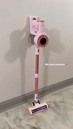 a pink and white floor sweeper in front of a wall with the words my new vacuum on it