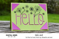 a card with the word hello written in pink and green on it sitting on top of a wooden table