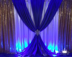 purple and gold wedding backdrop with sequins on the side, draped in blue fabric