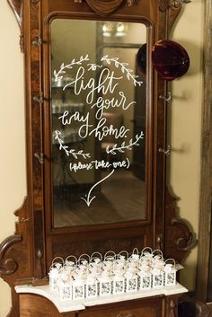 a mirror with writing on it sitting next to a table filled with small boxes and cups