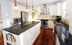 a large kitchen with white cabinets and black counter tops, along with an island in the middle