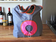 a gray bag with a pink donut hanging from the side on top of a wooden table