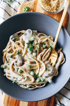 pasta with mushrooms and parsley in a bowl on a wooden cutting board next to a jar of seasoning