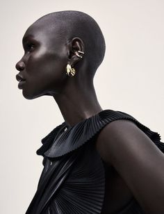 a woman with black hair and gold earring on her head, wearing a black dress