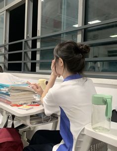 a woman sitting at a table with books and a cup in front of her,