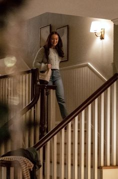 a woman standing on the top of a stair case next to a handrail in a house