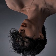 a man is upside down in the air with his head tilted to the side and hair on his face