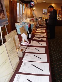 there are many papers lined up on the long table with wine bottles next to it