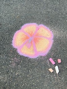 an orange and pink object on the ground with crayons in front of it