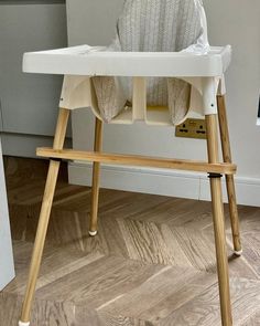 a baby highchair sitting on top of a hard wood floor next to a wall