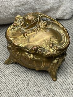 an ornate gold box sitting on the floor next to a white towel and pillow in a room