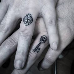 two people with tattoos on their fingers and one has a heart shaped key tattoo on the middle finger