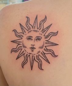 a sun tattoo on the back of a woman's shoulder