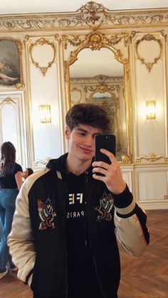 a young man taking a selfie in front of a mirror with his cell phone