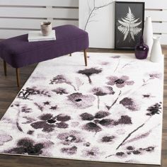 a white rug with black flowers on it in a room next to a purple chair