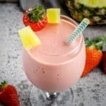 a smoothie with strawberries and pineapple on the side